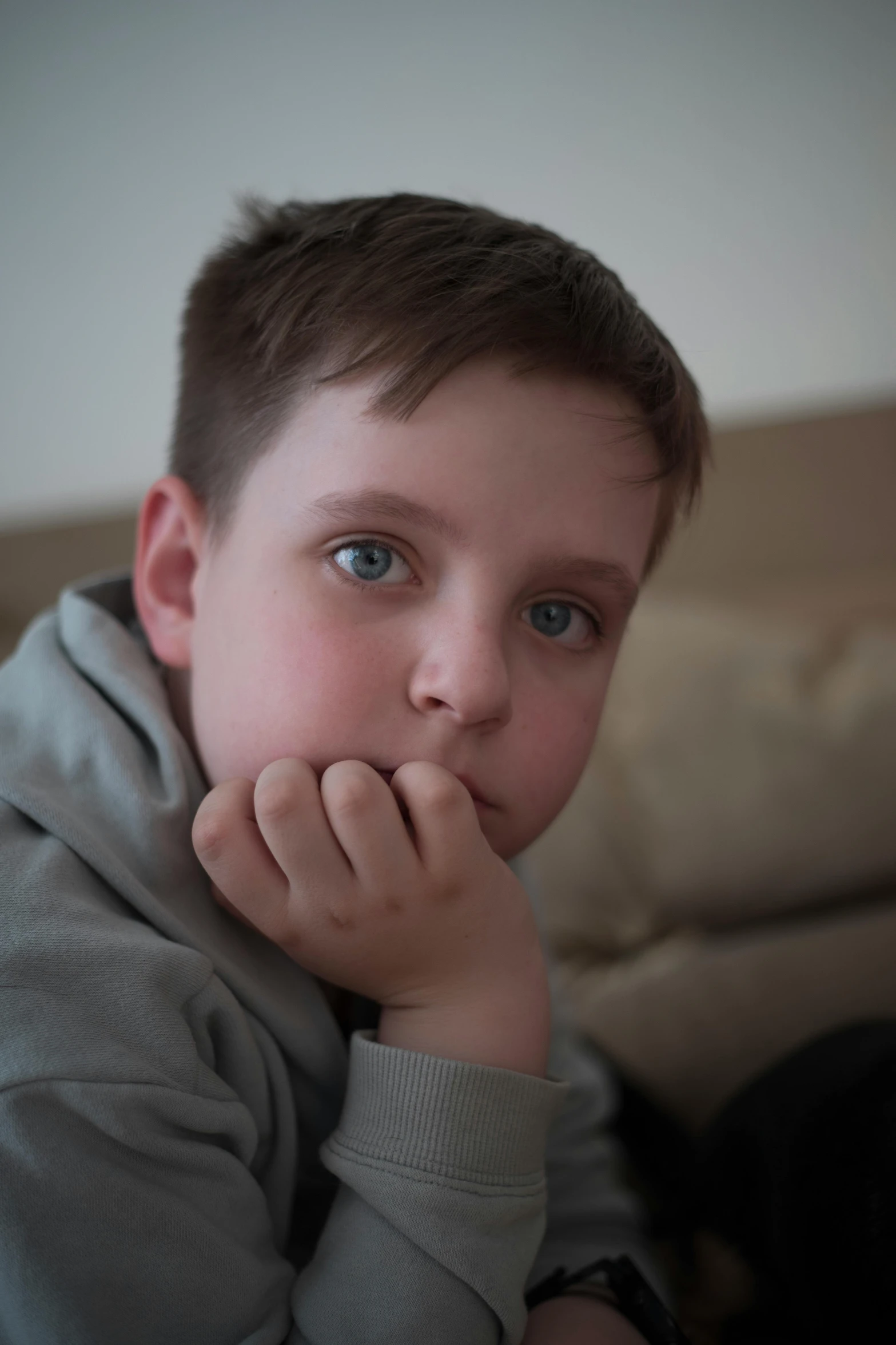 a boy with one eye looking up sitting in a living room