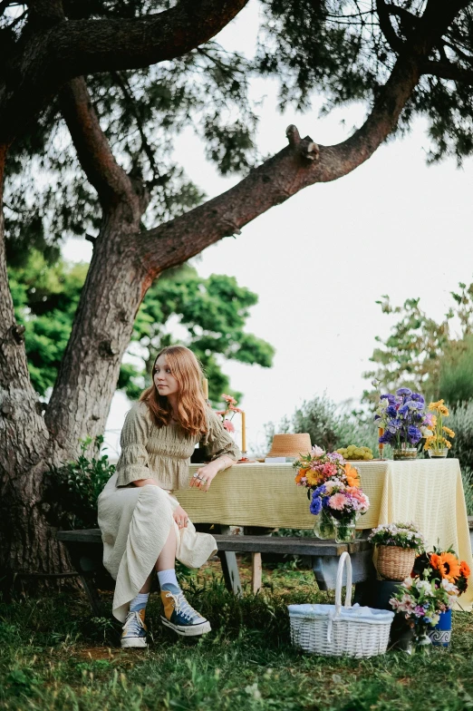 a woman sitting on a bench in the park by some flowers
