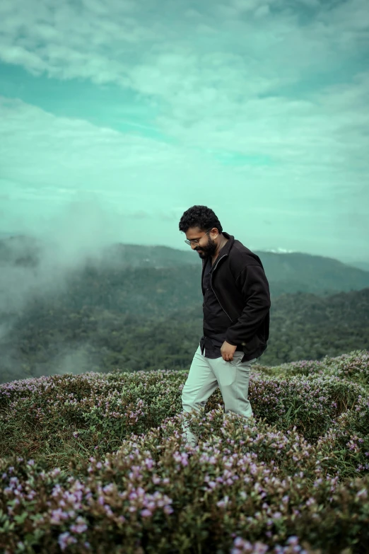 a man is walking through a meadow with flowers