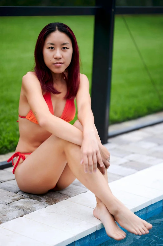 young asian woman in swimsuit posing by a pool