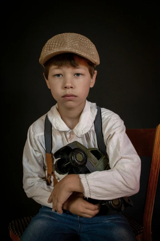  sitting on chair with hat and wearing overalls