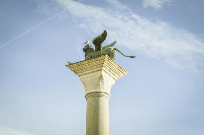 a statue on top of a column under a clear blue sky