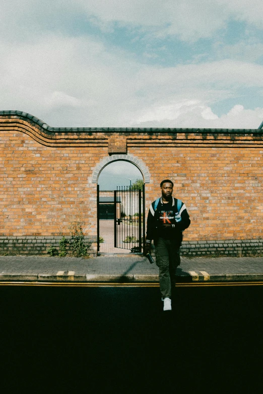 a young man sitting against a brick building