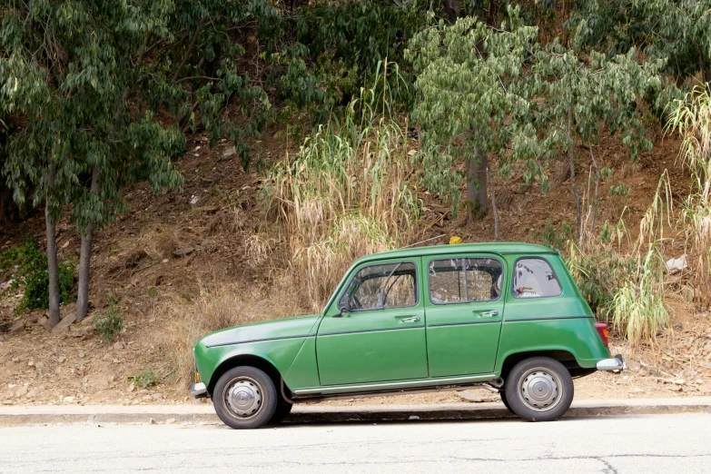 a green old car is parked on the side of the road