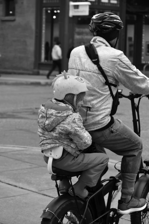 an adult rides on a bicycle with a child on the back