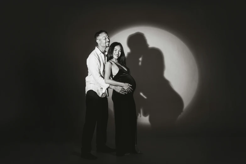 a pregnant couple in front of a shadow of a person's hand