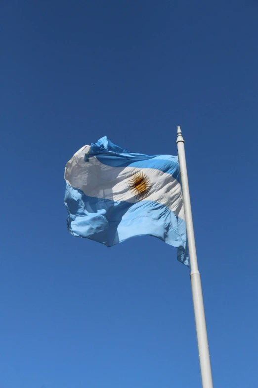 a flag flying in the wind under a clear blue sky