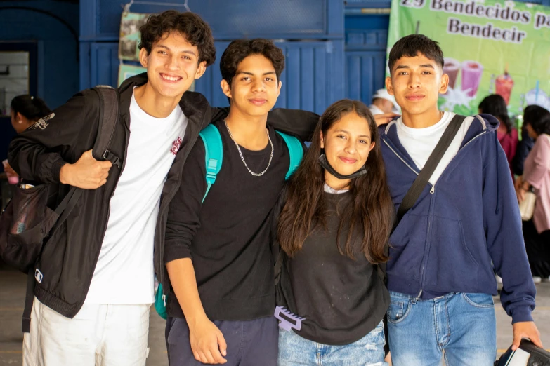 four young men standing together in front of a poster