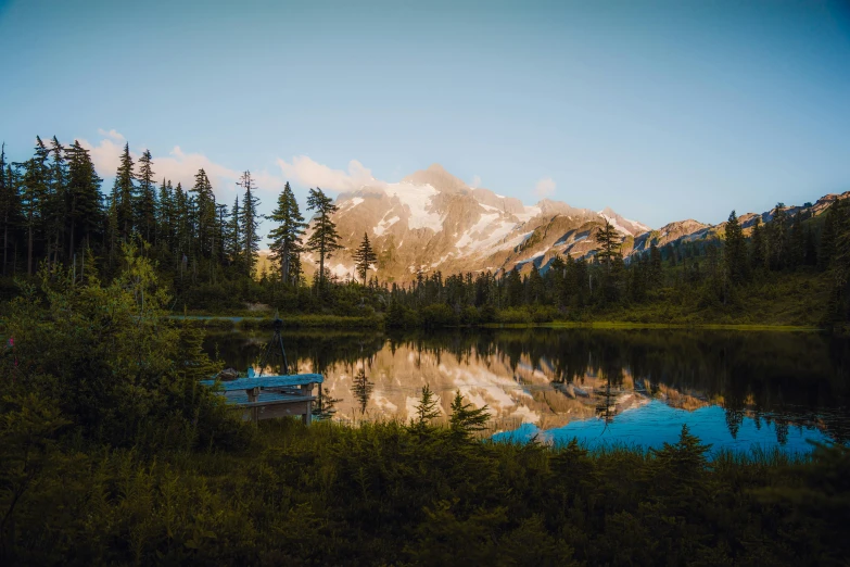 mountains are shown near the lake and pine trees