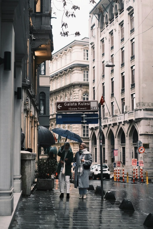 three people walking on a sidewalk with an umbrella