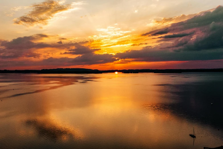 an ocean at sunset with clouds in the sky