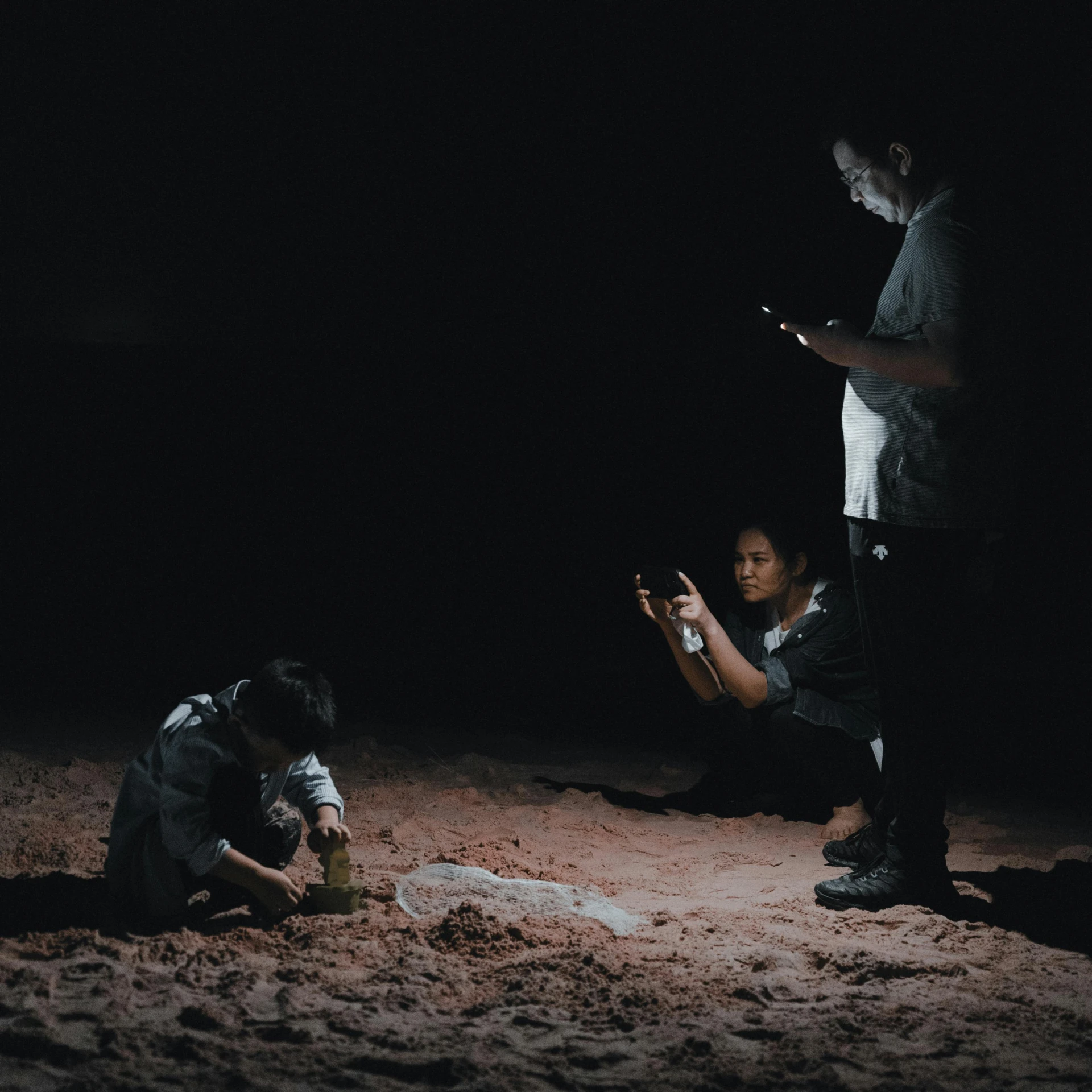 two men in the dark taking pictures with their cell phones