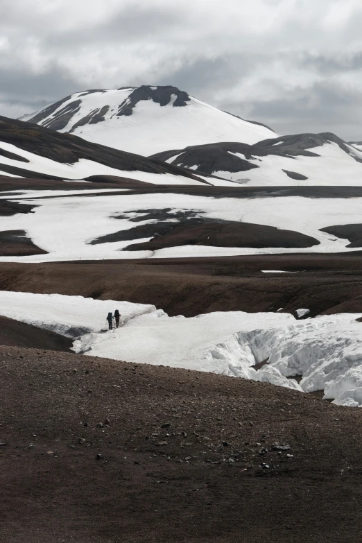 two people walking in the snow towards mountains