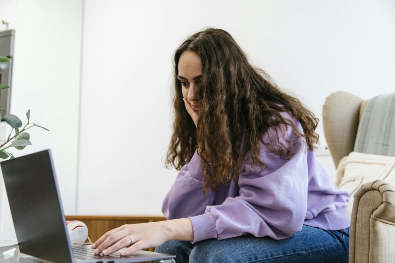 a woman is typing on her laptop while sitting in a chair