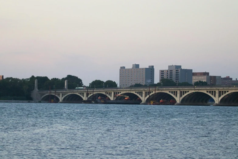 there are two bridge spanning a river with buildings in the background