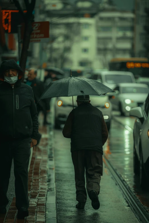 a man walking down the sidewalk in the rain with a umbrella