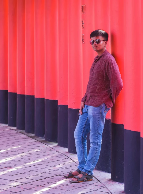 a man leaning against a building that is painted in red and blue