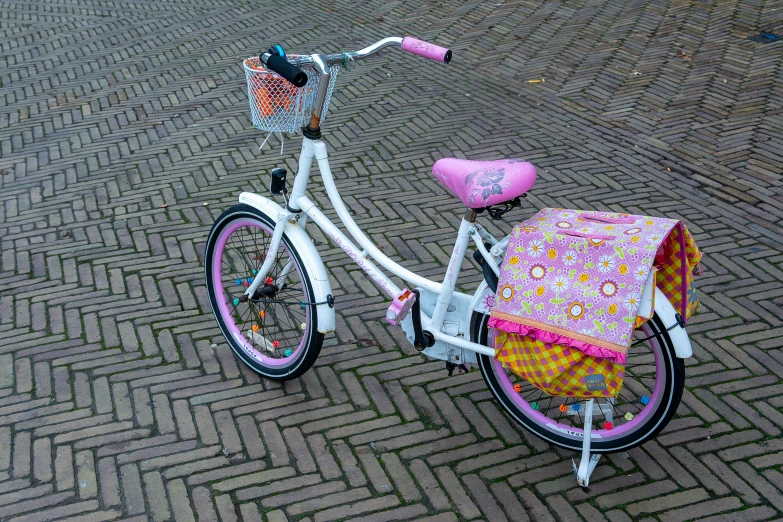 a white bike is with a pink seat and pink flowers on it