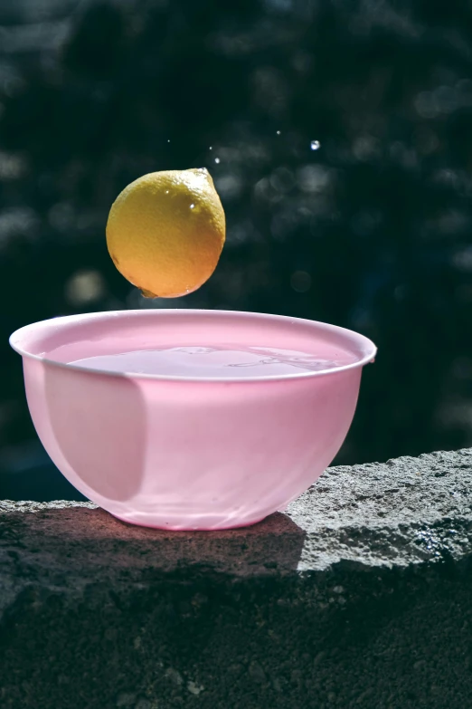 an orange being squeezed into a bowl with a fruit on top