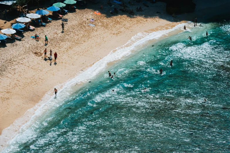 people are walking on the beach near the water