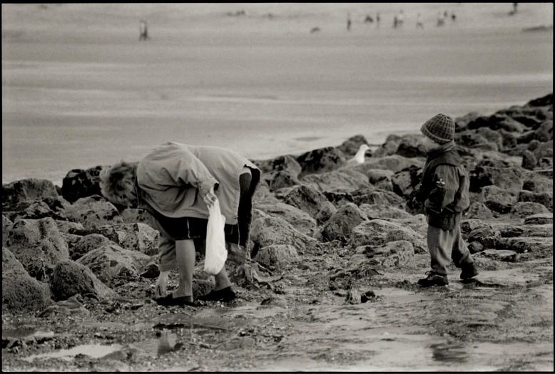 an elderly man and a  picking up soing on the rocks