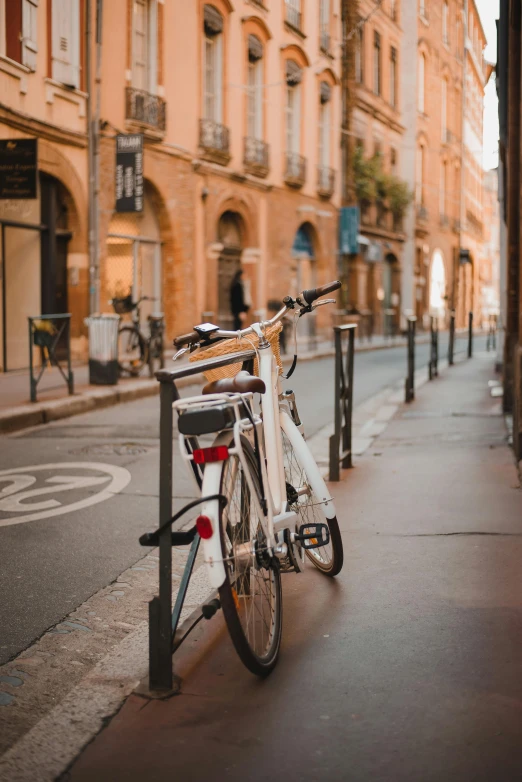 the bicycle is  up to the pole next to the bike rack