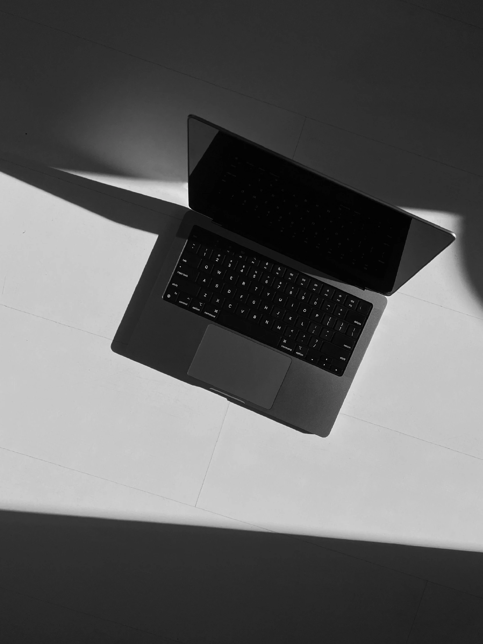 a laptop computer sits on the surface of a white table