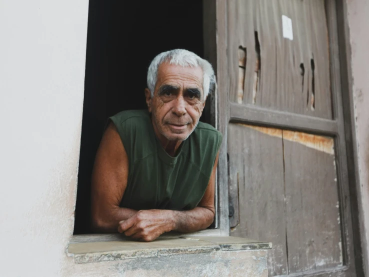 an elderly man looking out the window of a building