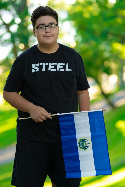 a young man poses with the flag of the country of el salvador