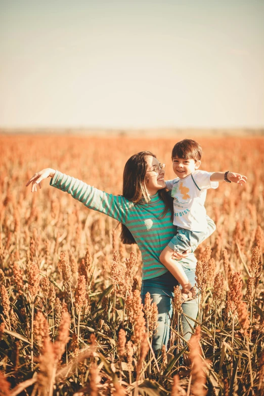 a girl holding a boy while standing in a field