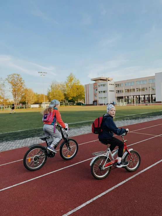 two children are riding their bikes on the track