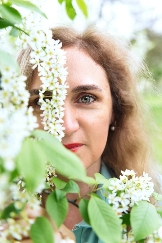 a woman looking through the nches of a flowering tree