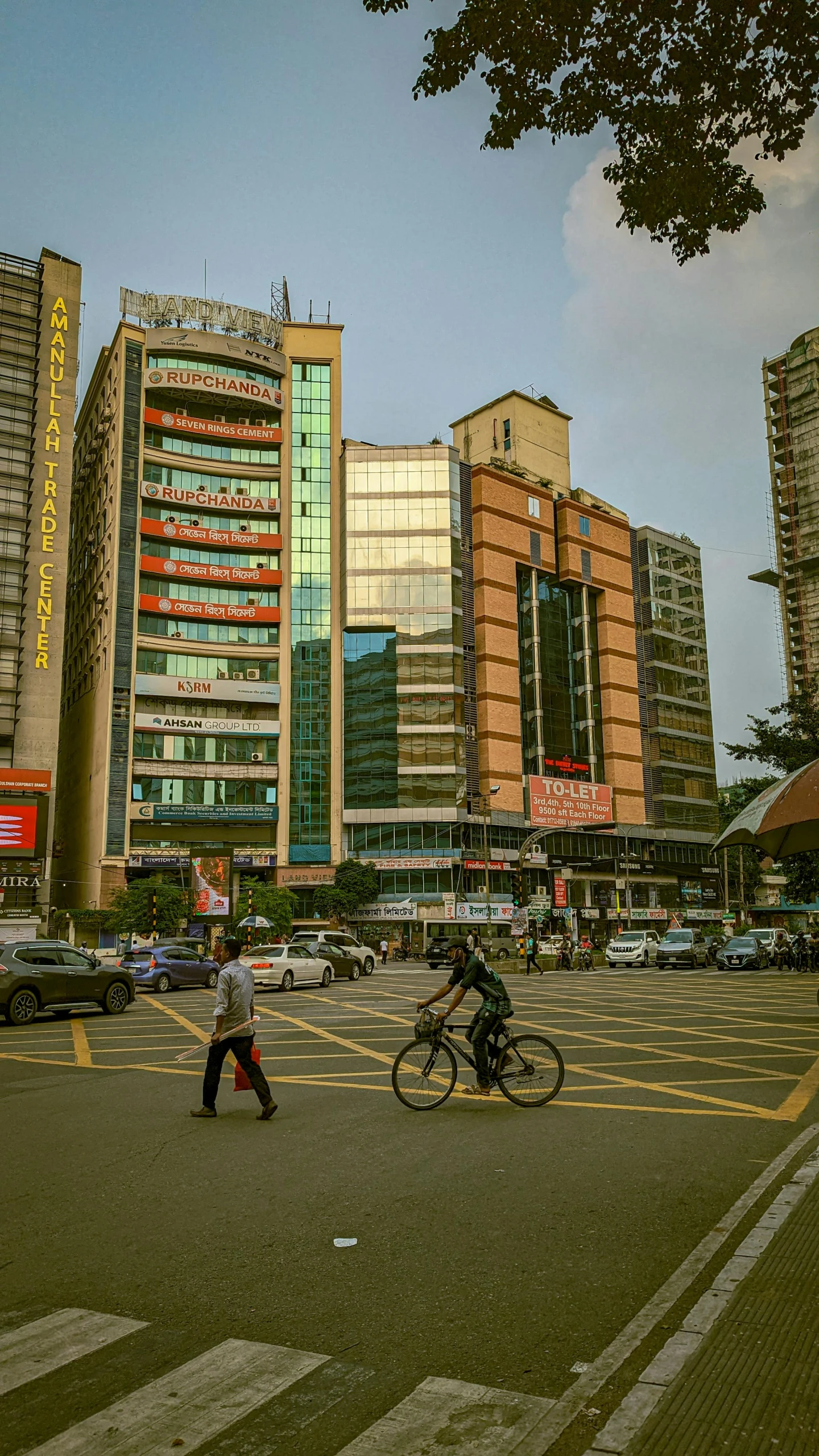 people crossing a city intersection with tall buildings behind them