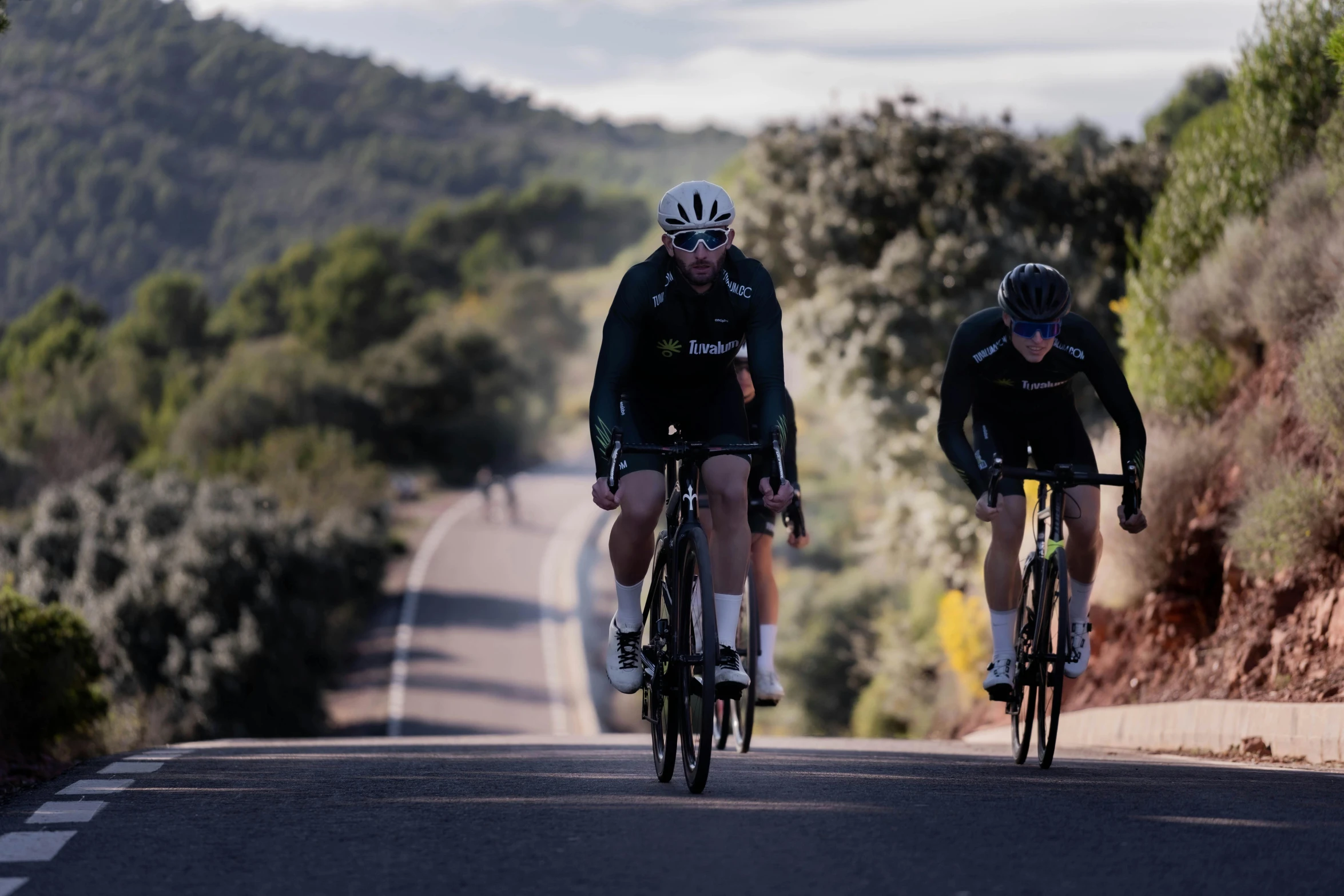 a couple of people riding on top of bikes down a road