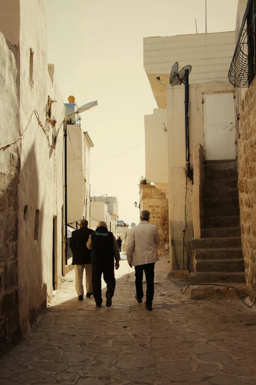 three people walking down a narrow street together