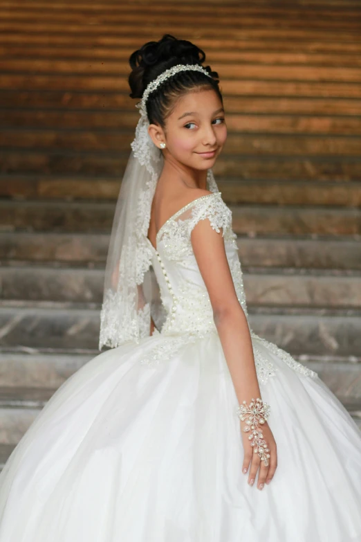 a young bride standing on the stairs wearing her wedding gown