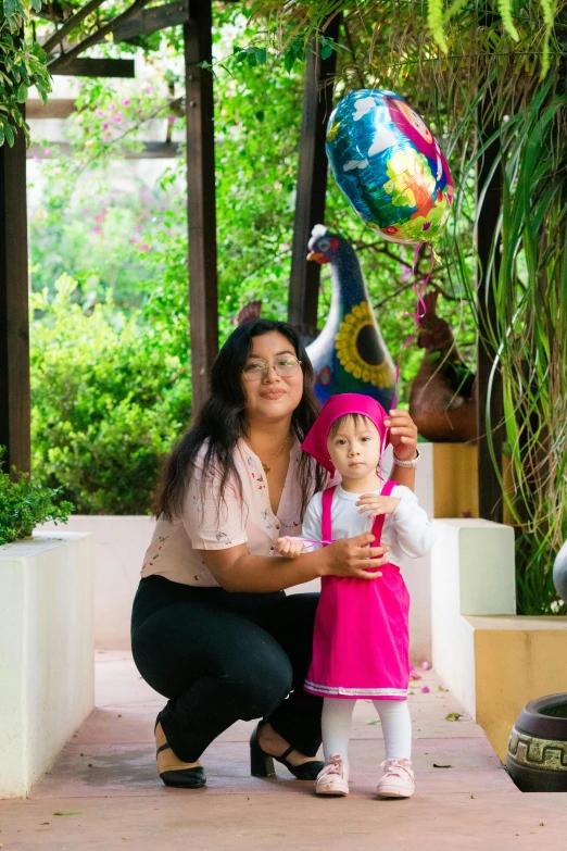 a woman with a child that is holding up balloons