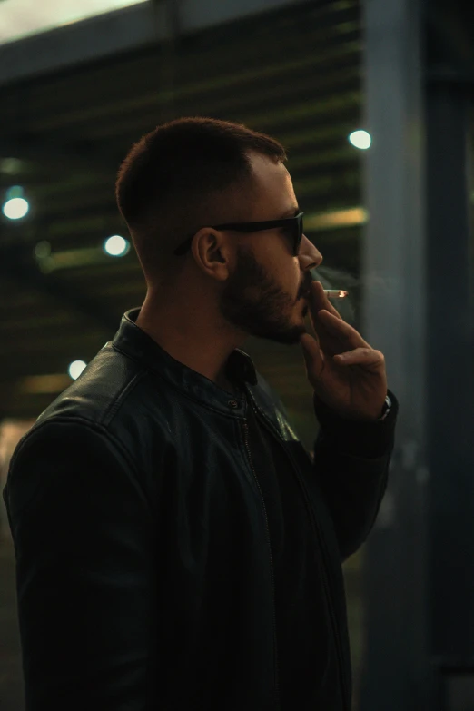 a man wearing a leather jacket and glasses, smoking a cigarette