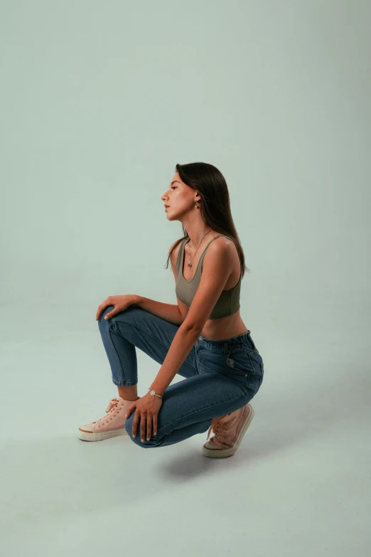 a woman squatting down looking up with one hand on her hips