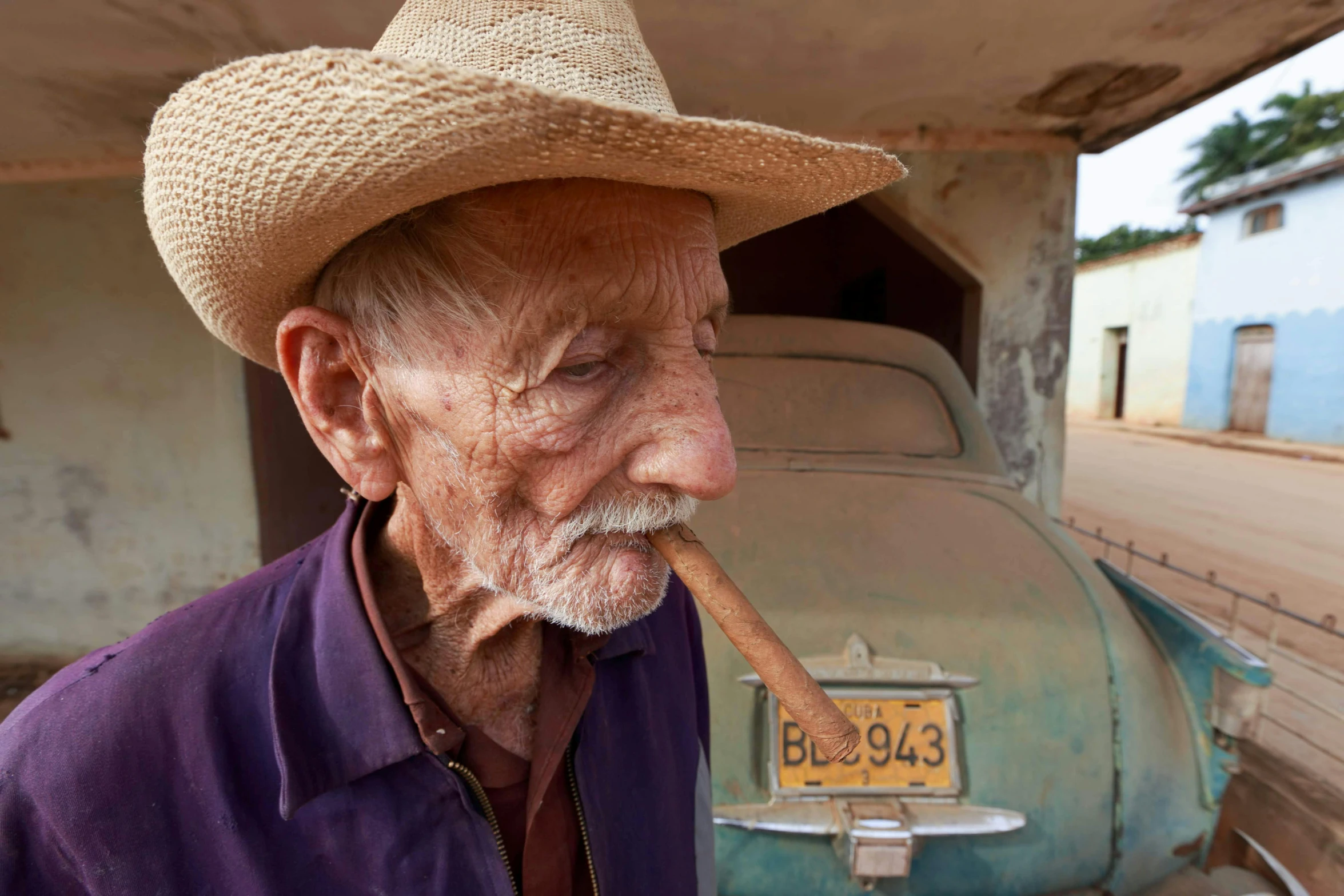 an old man with a straw hat blowing a stick