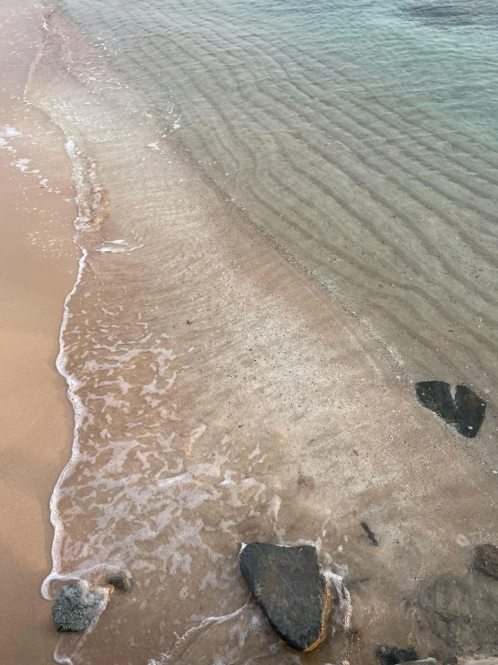 an ocean beach that has rocks in the sand