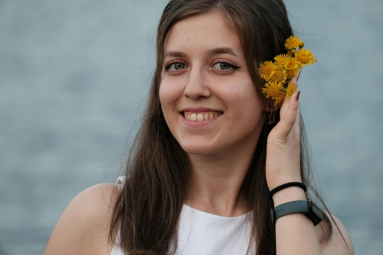 a young lady holds flowers up to her head