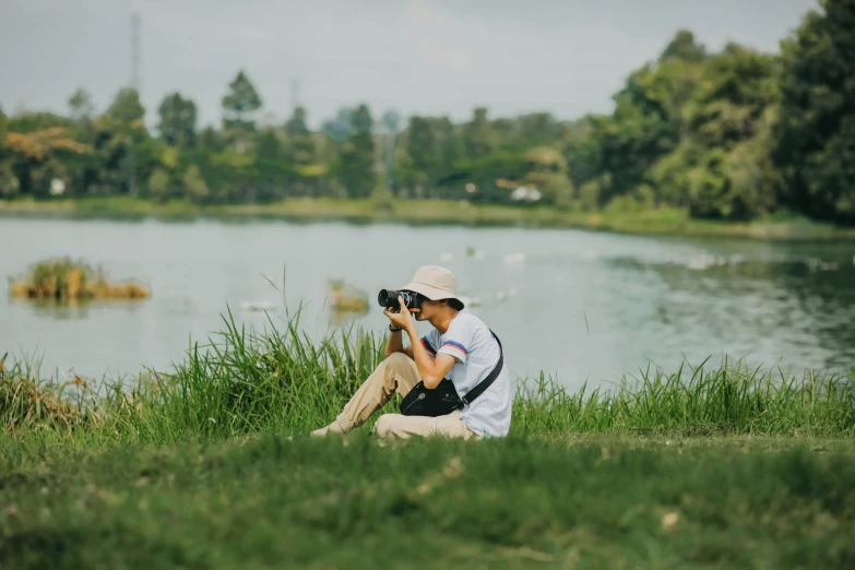 man in white shirt and white hat with camera by water