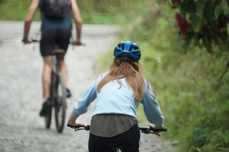 the two people ride bicycles down a path