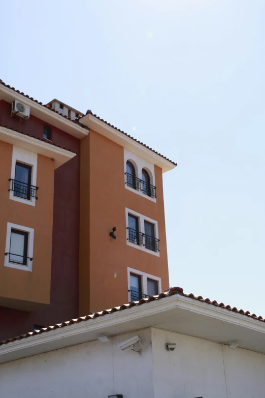 an orange building with white windows on the roof and a red balcony