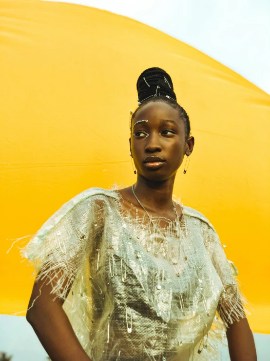 a woman standing under a yellow umbrella in a dress