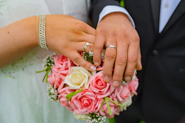 a bride and groom holding hands and a bouquet of roses