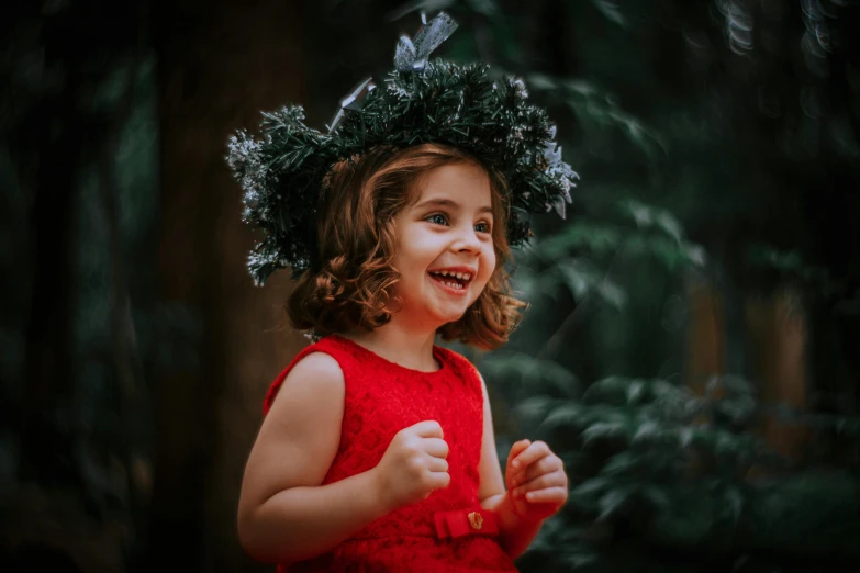 a little girl in a red dress with a wreath on her head