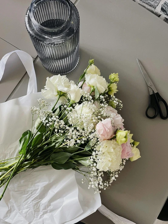 bouquet of flowers is laid out on a table beside scissors