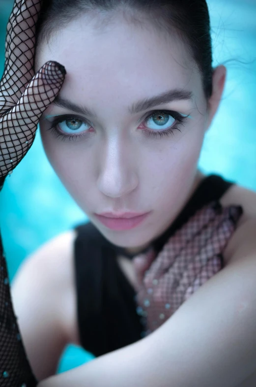 a woman with blue eyes and gloves posing for a po